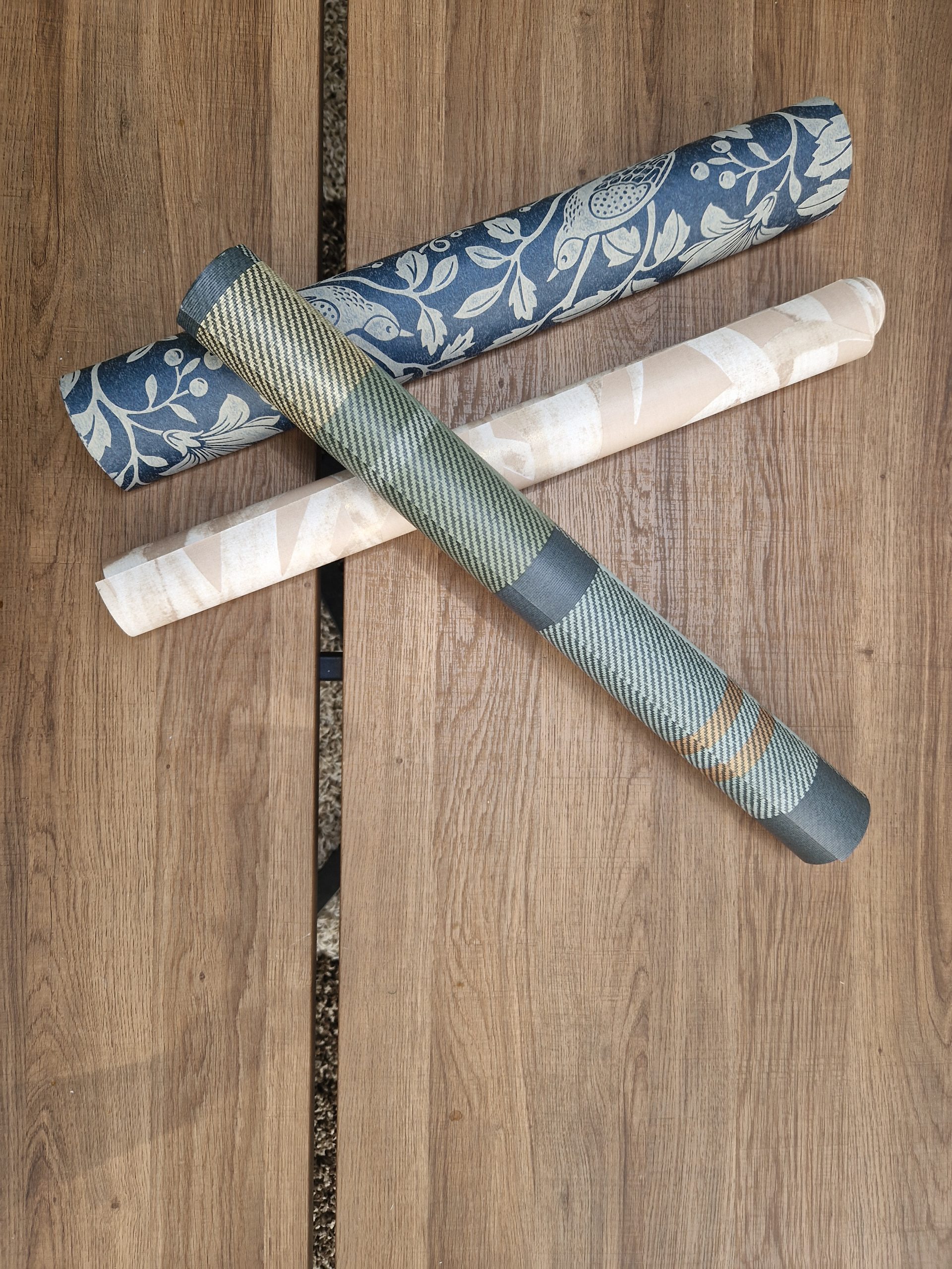 Rouleaux de papier peint à motifs posés sur un sol imitation bois